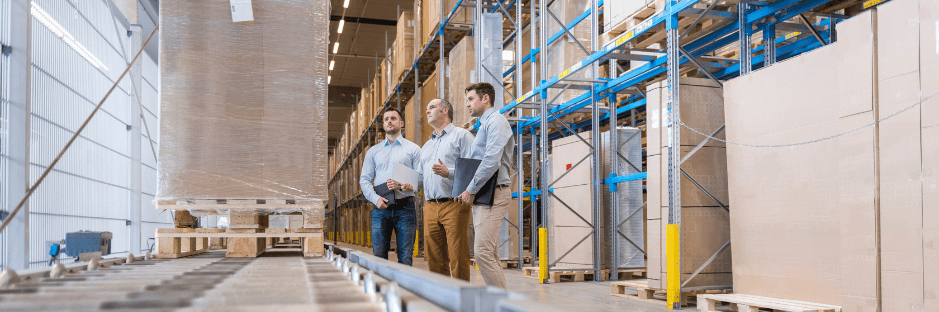 three men in a stock storage looking at a package