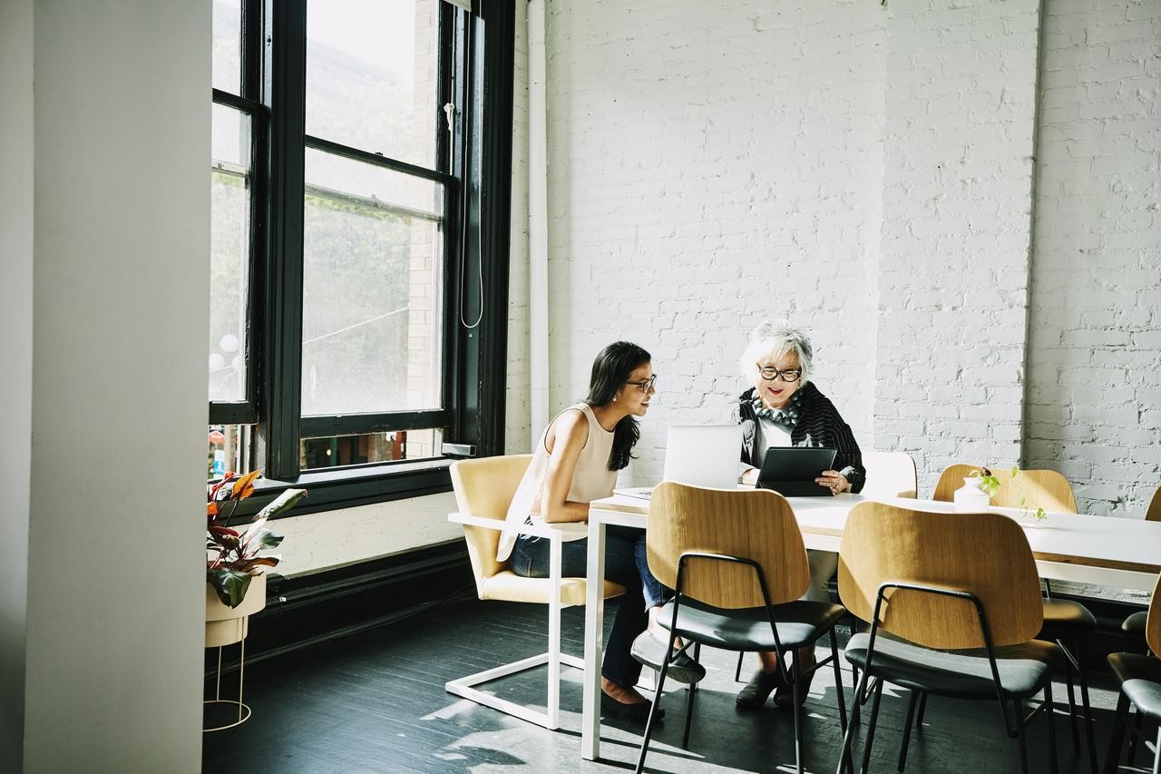 two women discussing around a table with a screen