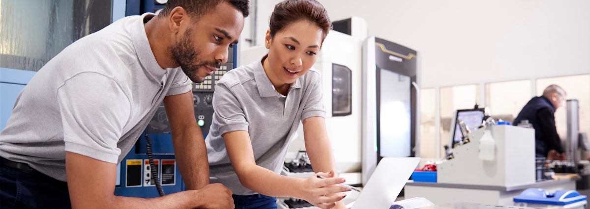 2 workers in a factory in front of a laptop